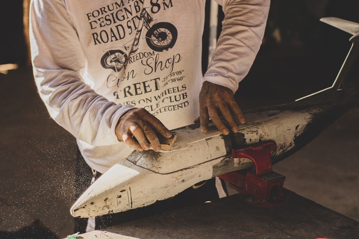 Hands sanding a repair patch on a board in the workshop