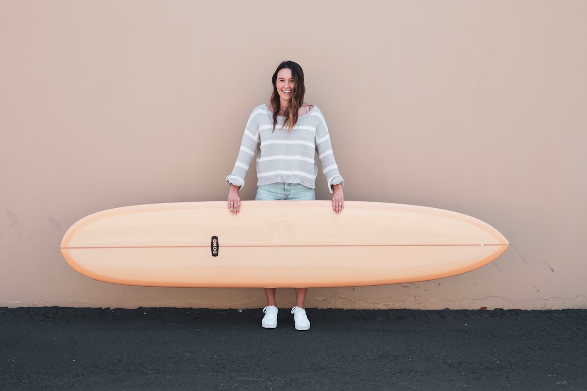 A rider carrying a second-hand board against a painted wall